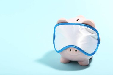 Mavi arka planda uyku maskesi olan piggybank. Minimalizm conc