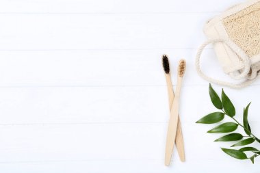 Beyaz ahşap masa üzerinde bez ve yeşil yapraklı Bambu diş fırçaları
