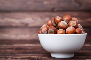 Kahverengi ahşap masa üzerinde kase olgun fındık