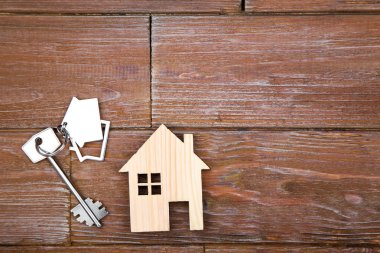 Kahverengi ahşap masa üzerinde ev sembolü ile gümüş anahtar