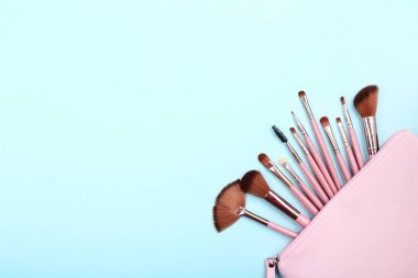 Mavi arka plan üzerinde çanta makyaj fırçaları seti