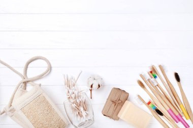 Beyaz ahşap masa üzerinde sabun, bez ve pamuk çubukları ile Bambu diş fırçaları