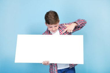 Mavi arka plan üzerinde beyaz boş tahta tutan genç çocuk