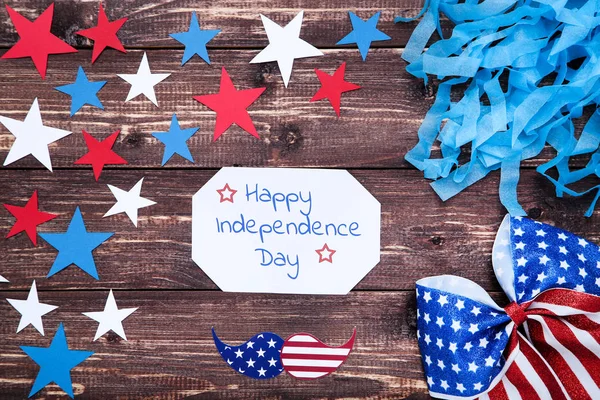 Texto Feliz Día de la Independencia con estrellas de papel y arco en wo marrón — Foto de Stock