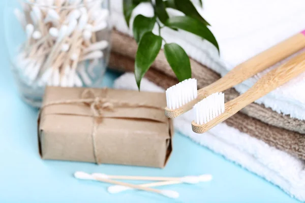 Bamboo toothbrushes with cotton sticks and towels on blue background — Stock Photo, Image