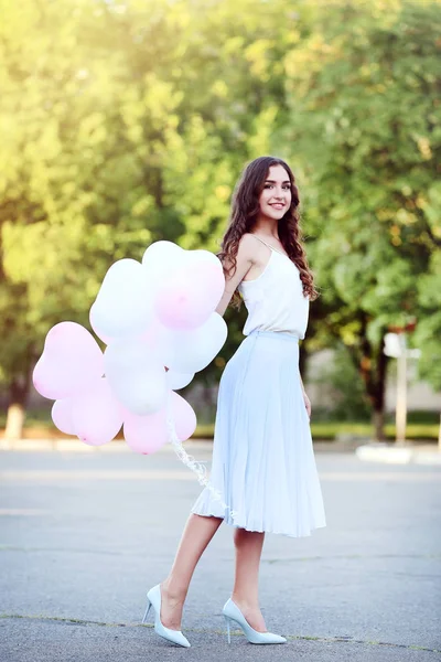 Young girl with heart balloons in the park — Stock Photo, Image