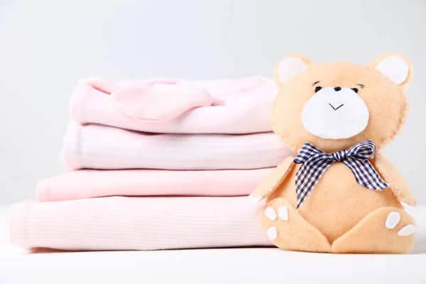 Vêtements de bébé pliés avec jouet ours doux — Photo