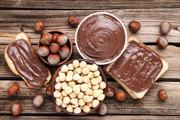 Roti dengan coklat cair dan hazelnut di atas meja kayu cokelat — Stok Foto