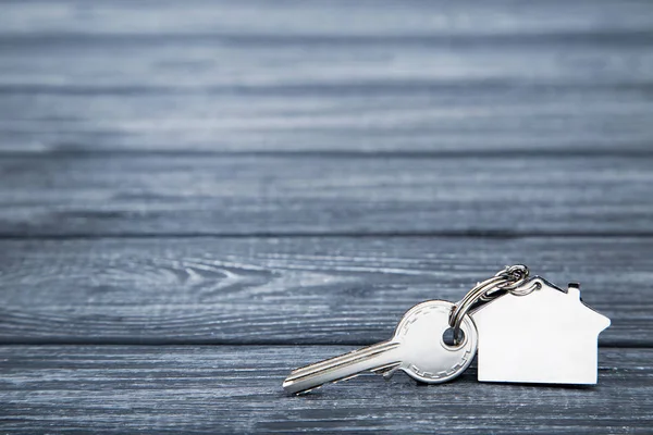 Silver nyckel med husets symbol på svart träbord — Stockfoto