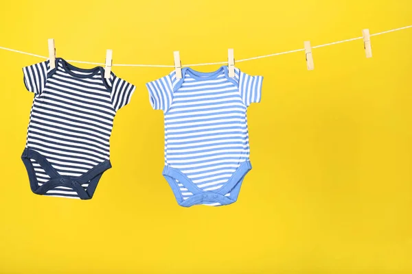 Ropa de bebé colgada sobre fondo amarillo —  Fotos de Stock