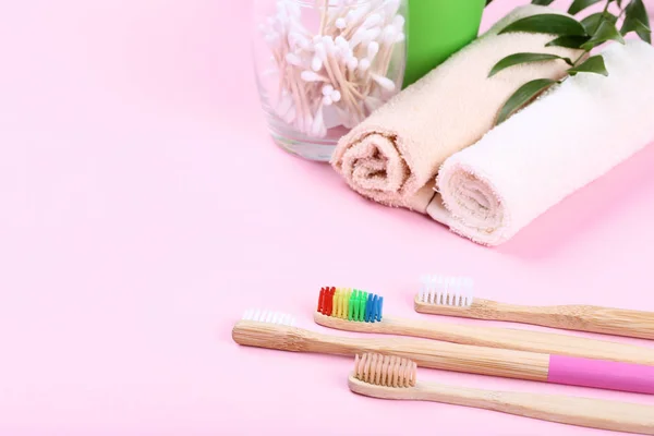 Bambuszahnbürsten mit Baumwollstäbchen und Handtüchern auf rosa Backgr — Stockfoto