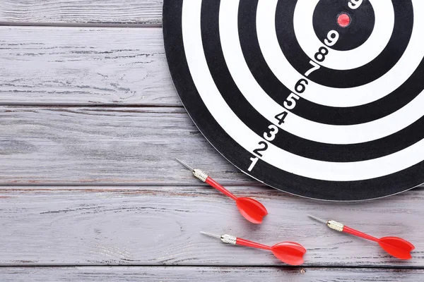 Dartboard com dardos na mesa de madeira — Fotografia de Stock