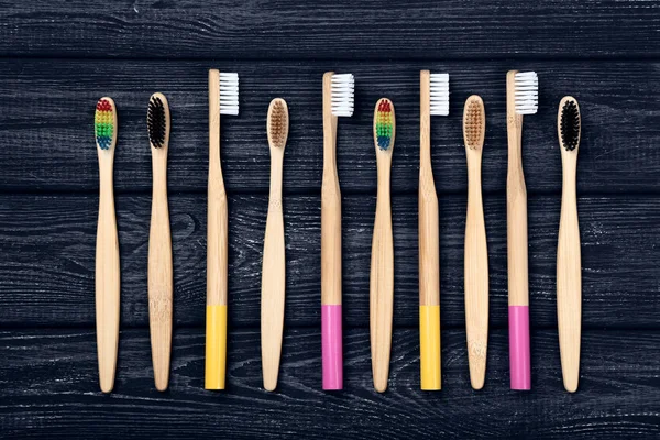 Bamboo toothbrushes on black wooden table — Stock Photo, Image