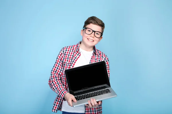 Молодий хлопчик тримає ноутбук на синьому фоні — стокове фото