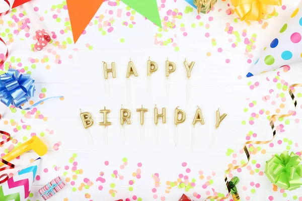 Happy Birthday candles with party decorations on white wooden ta — Stock Photo, Image