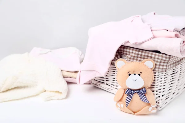 Roupas de bebê dobradas com brinquedo de urso macio — Fotografia de Stock