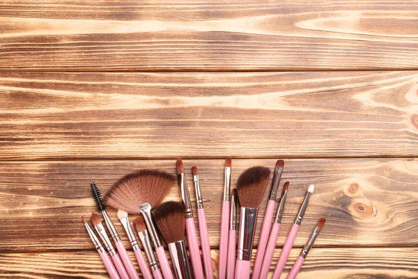 Набор кистей для макияжа на коричневом деревянном столе — стоковое фото
