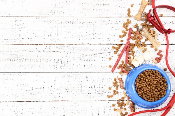 Dry pet food in bowl with red collar on white wooden table — Stock Photo, Image