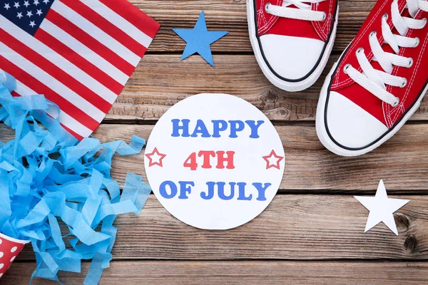Text glücklich 4. Juli mit amerikanischer Flagge und Turnschuhen auf Holz — Stockfoto