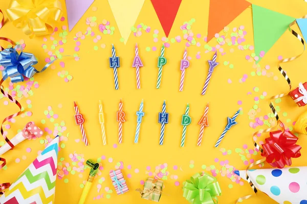 Feliz cumpleaños velas con decoraciones de fiesta en el fondo amarillo —  Fotos de Stock