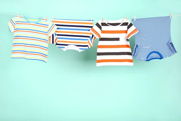 Vêtements bébé suspendus sur fond bleu — Photo