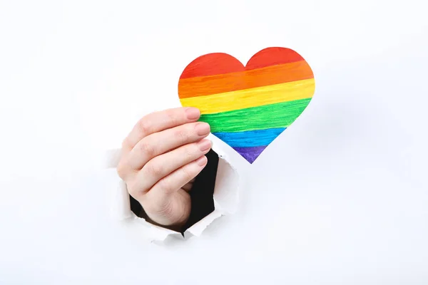 Hand holding papier regenboog hart van wit gescheurde papier — Stockfoto