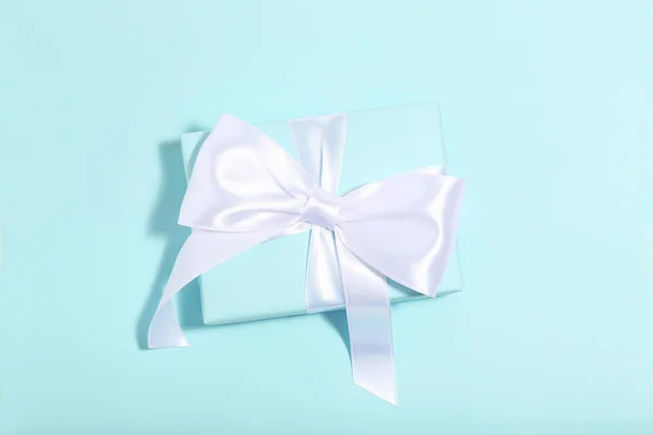 Gift box with ribbon bow on blue background. Minimalism concept — Stock Photo, Image