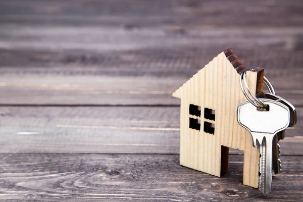 Срібний ключ з символом будинку на коричневому дерев'яному столі — стокове фото