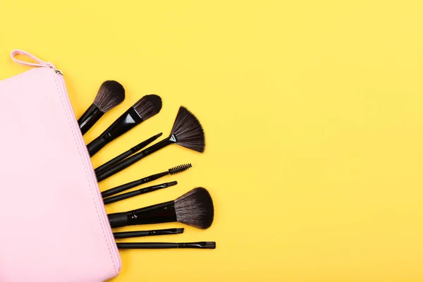 Set of makeup brushes in bag on yellow background — Stock Photo, Image