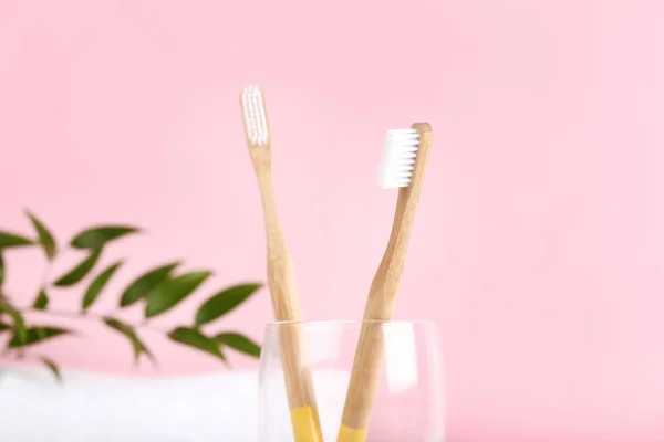 Bamboo toothbrushes in glass on pink background — Stock Photo, Image