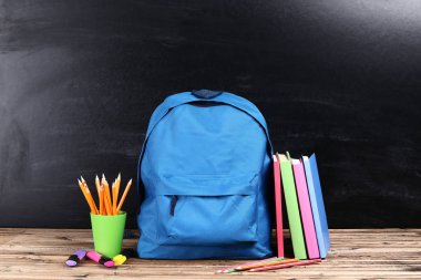 Siyah arka planda okul malzemeleriyle dolu sırt çantası.