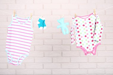 Duvarda yumuşak oyuncaklı bebek kıyafetleri asılı.