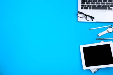 Tablet, gözlüklü dizüstü bilgisayar ve mavi bac üzerinde kol saati