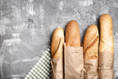 Gri ahşap masa üzerinde peçete ile taze bagetler