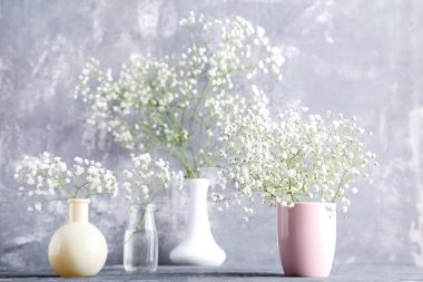 Beyaz Gypsophila çiçekler vazo, fincan ve cam şişe gri 
