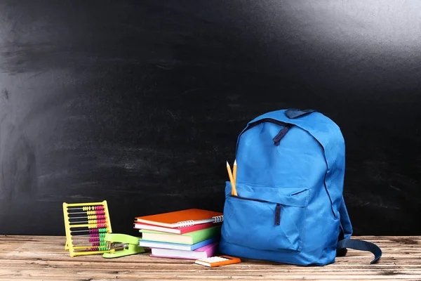 Rucksack mit Schulmaterial auf schwarzem Hintergrund — Stockfoto