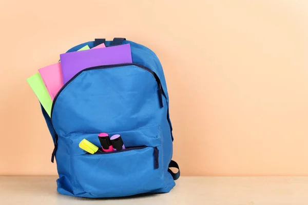 Рюкзак з шкільними приладдям на бежевому фоні — стокове фото