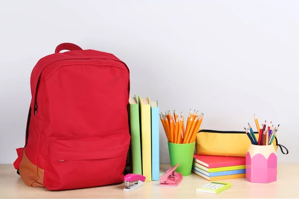 Gri arka planda okul malzemelerinin olduğu sırt çantası. — Stok fotoğraf