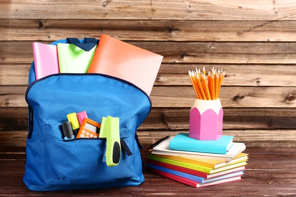 Backpack with school supplies on brown wooden table — Stock Photo, Image