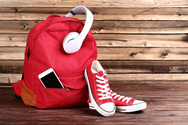 Mochila escolar com fones de ouvido, smartphone e tênis na testa — Fotografia de Stock