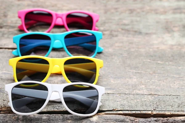 Kolorowe okulary przeciwsłoneczne na szarym drewnianym stole — Zdjęcie stockowe