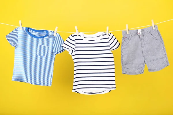 Bayi pakaian tergantung pada latar belakang kuning — Stok Foto