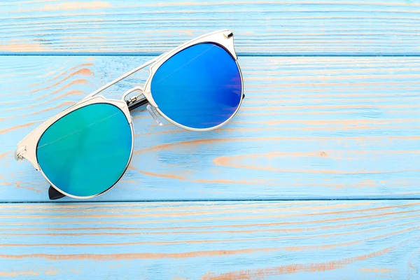 Nowoczesne okulary przeciwsłoneczne na niebieskim drewnianym stole — Zdjęcie stockowe