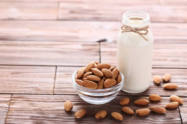 Leche de almendra en botella sobre mesa de madera marrón — Foto de Stock