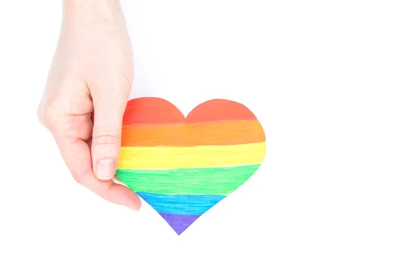 Weibliche Hand hält Regenbogenpapier Herz auf weißem Hintergrund — Stockfoto