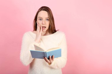 Pembe bir arka plan üzerinde kitapla genç kız