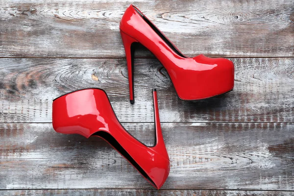 Czerwone buty na wysokim obcasie na brązowym drewnianym stole — Zdjęcie stockowe