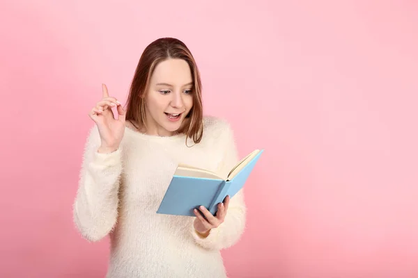 Młoda dziewczyna z książki na różowym tle — Zdjęcie stockowe