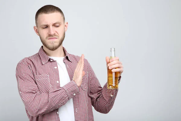 Jeune homme avec bouteille de bière sur fond gris — Photo