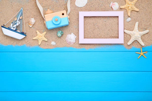 Seashells with beach sand and decorative ship on blue wooden tab — Stock Photo, Image